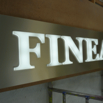 Caisson lumineux aluminium brossé avec le texte "FINEA" lumineux blanc en relief de 23mm