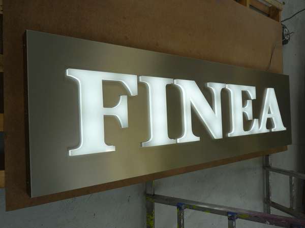 Caisson lumineux aluminium brossé avec le texte "FINEA" lumineux blanc en relief de 23mm